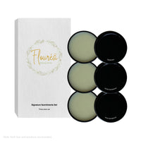 White Flourea Signature Scentiments Set box displayed next to three open black tins containing solid perfume.